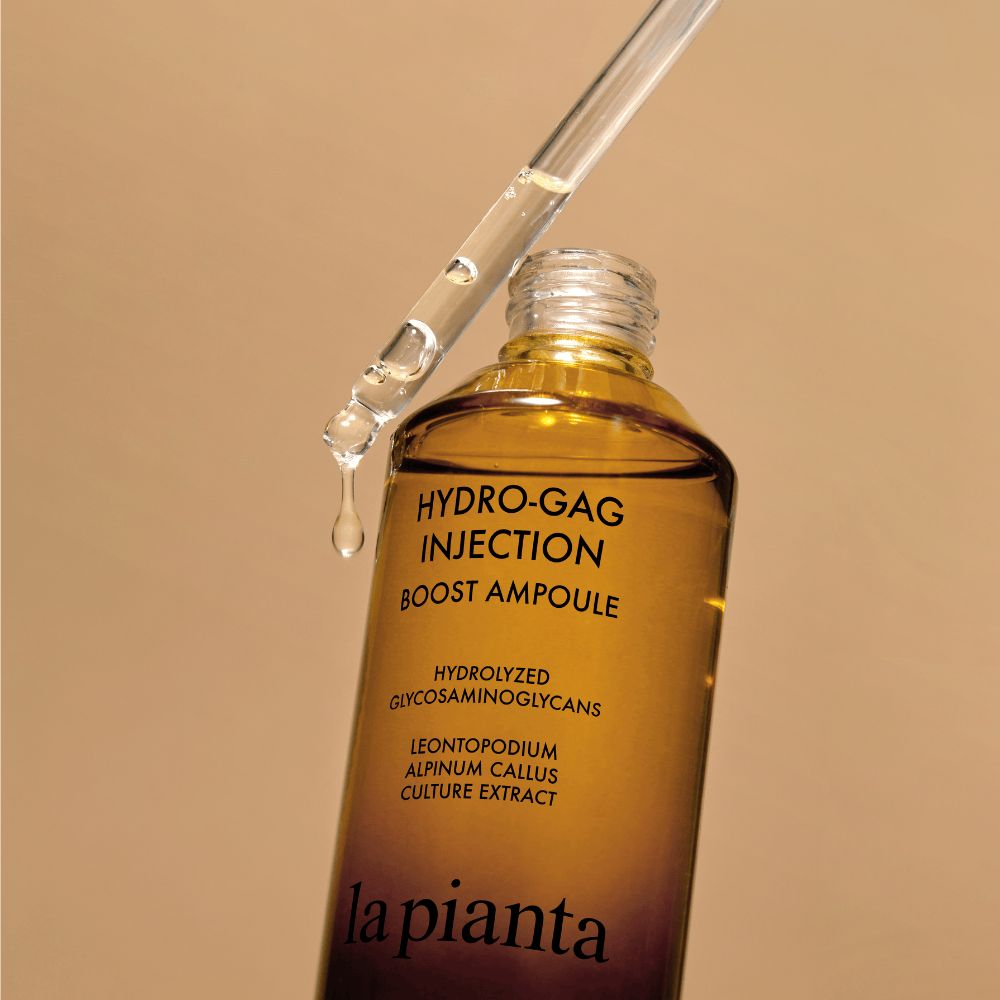 Flacone di vetro marrone con contagocce. Gocce che cadono. Scritta: HYDRO-GAG INJECTION BOOST AMPOULE. Marchio: la pianta.