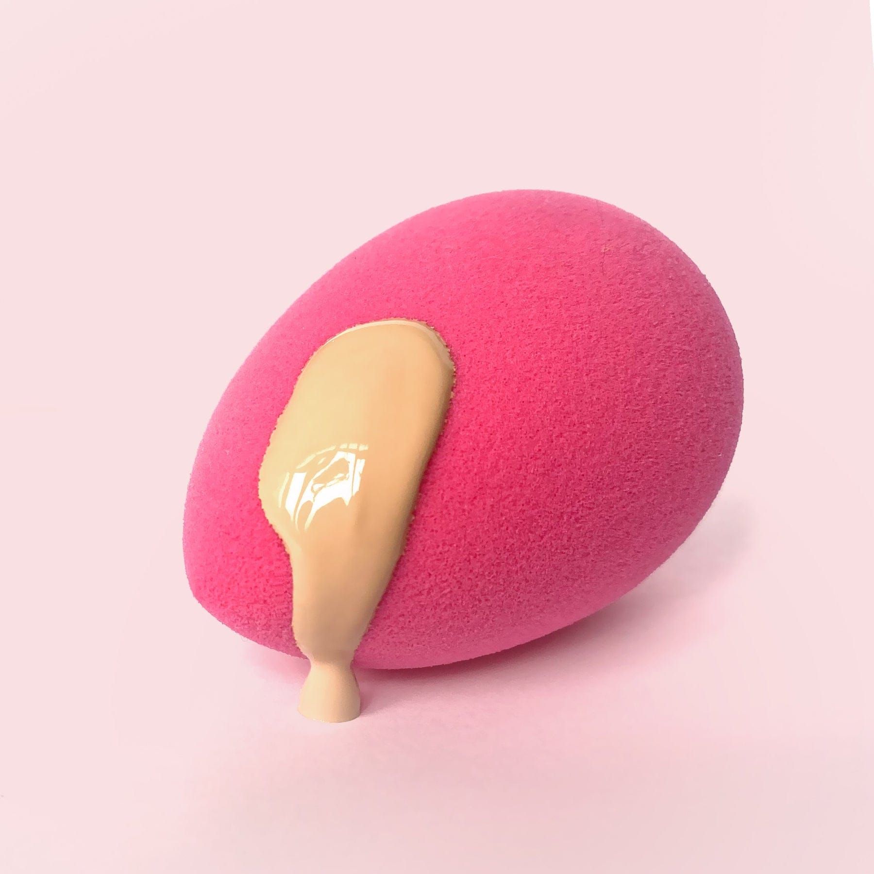 Una spugnetta per il trucco rosa con fondotinta liquido che cola.