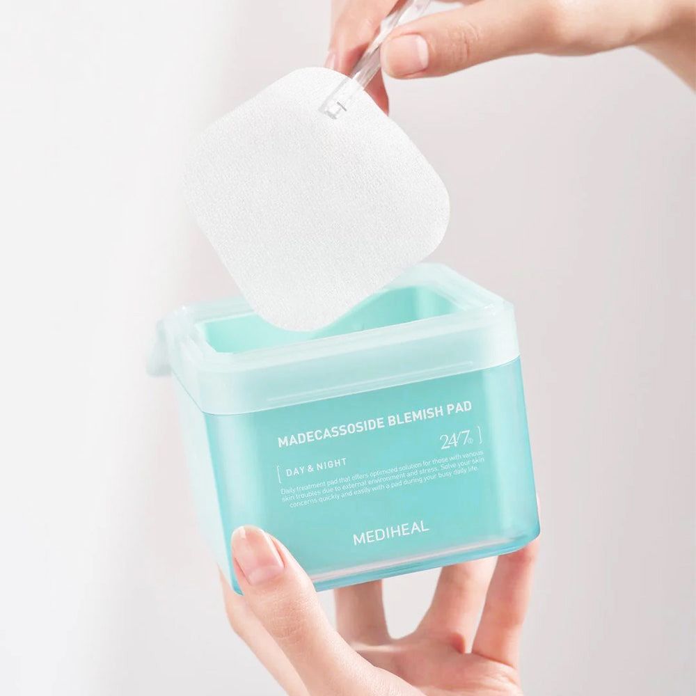 Mani che tengono un contenitore e un pad. Contenitore con scritta "MADECCASSOSIDE BLEMISH PAD". Marchio: MEDIHEAL.