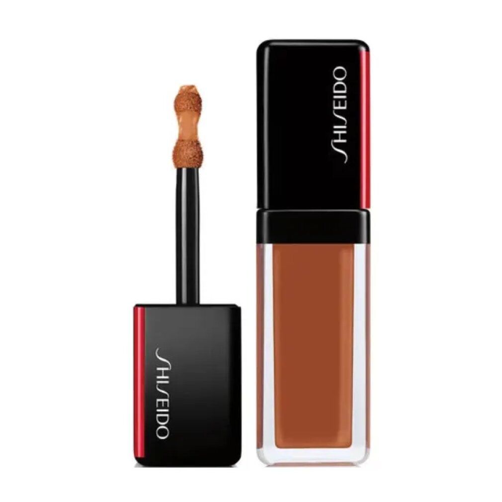 Flacone di correttore beige con tappo nero. Applicatore visibile. Logo Shiseido sul tappo.