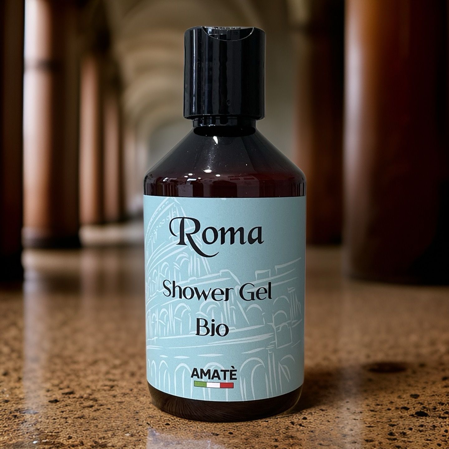 Flacone marrone con tappo nero. Etichetta: Roma, Shower Gel, Bio e Amatè. Su pavimento marmorizzato.