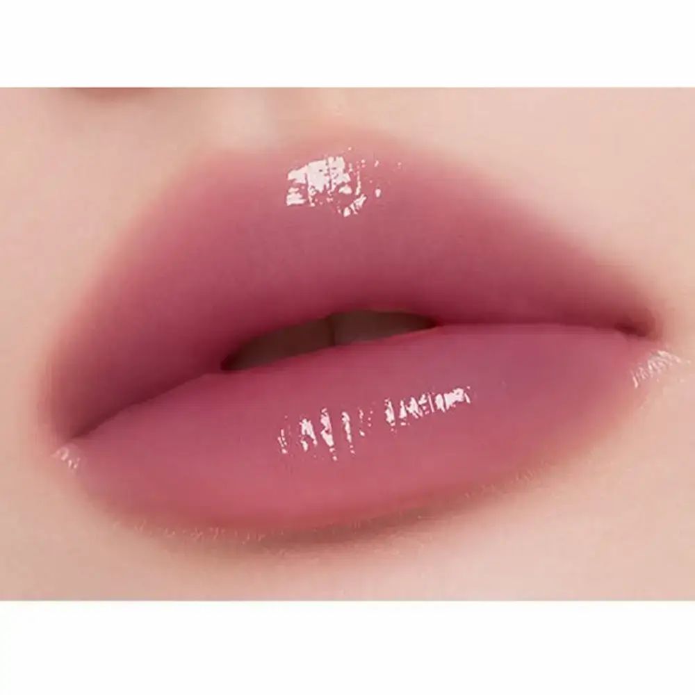 Primo piano di labbra dipinte con un rossetto rosa scintillante. Le labbra sono lucide e umide.