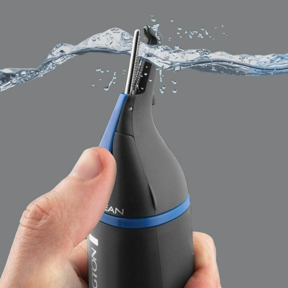 Primo piano di un trimmer naso/orecchie nero. L'acqua schizza sul dispositivo.