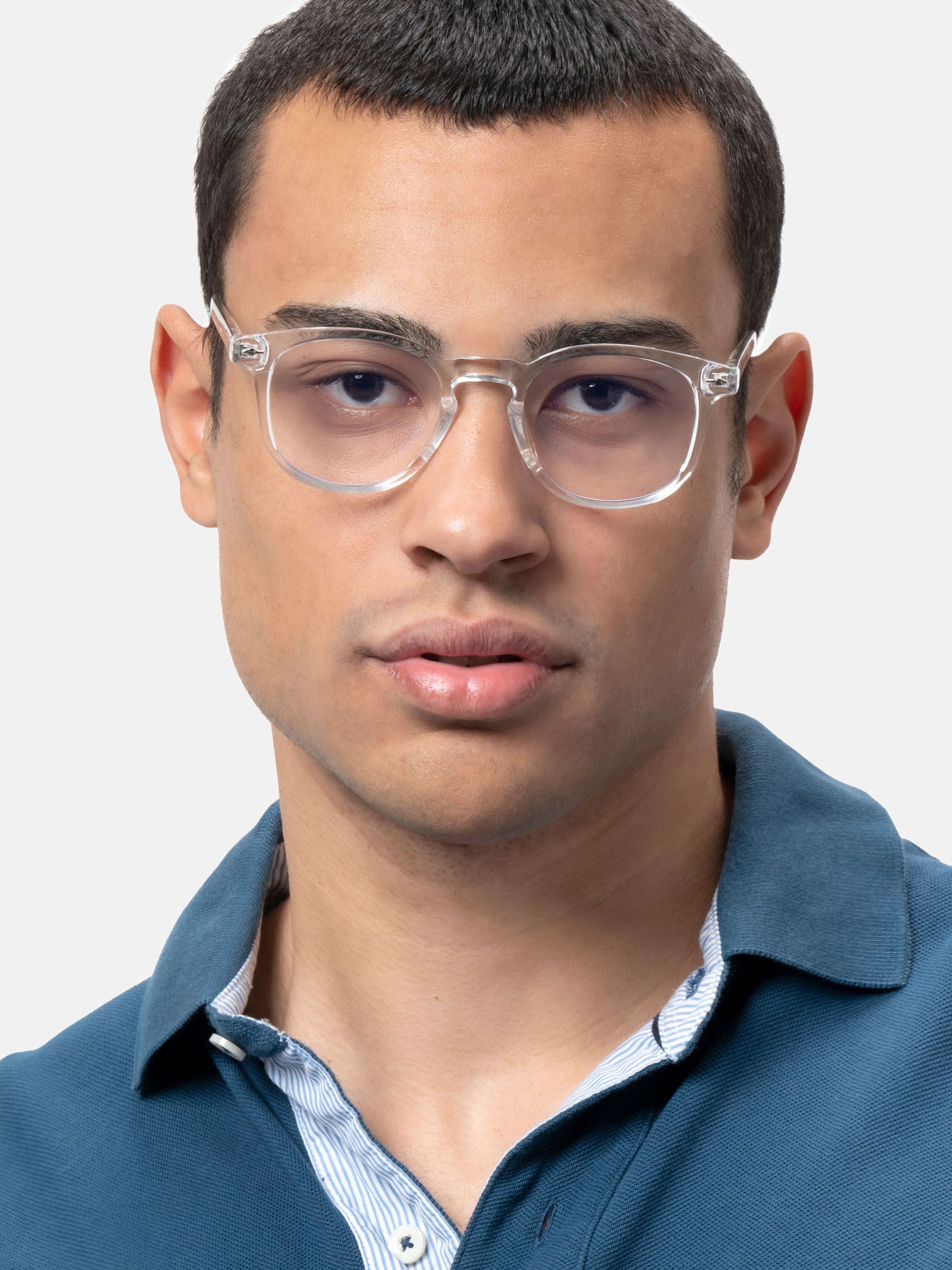 Uomo con occhiali trasparenti. Gli occhiali hanno una montatura quadrata. L'uomo indossa una polo blu.