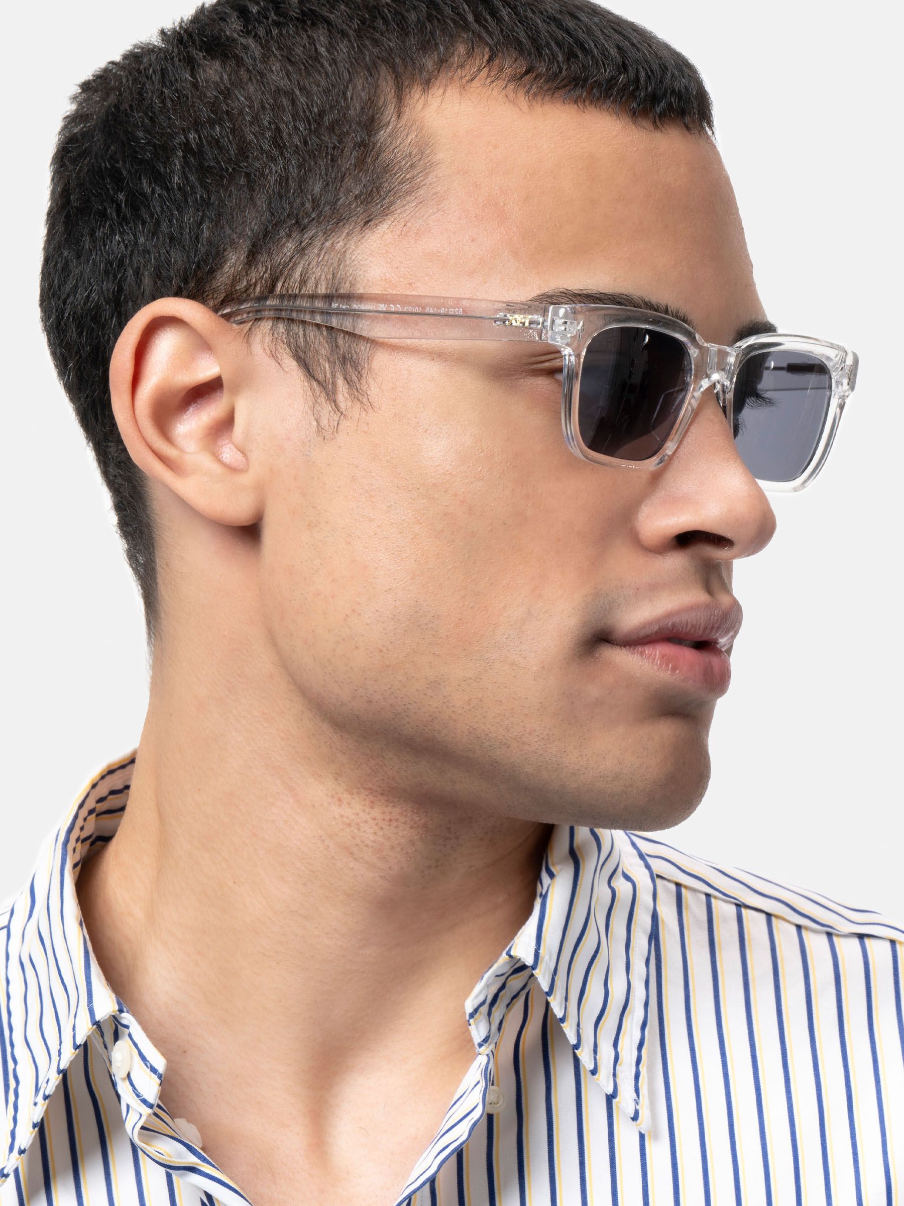 Uomo con occhiali da sole trasparenti, vista laterale. Lenti rettangolari, tonalità scura. Logo XFT.