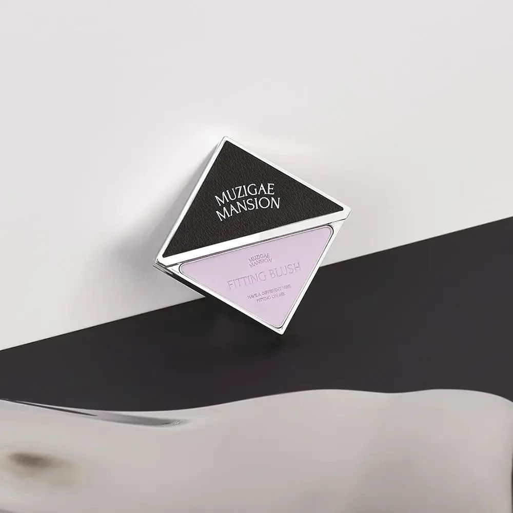 Fard in forma di diamante su sfondo bianco e nero. Marchio MUZIGAE MANSION e nome del prodotto visibili. Tonalità rosa.