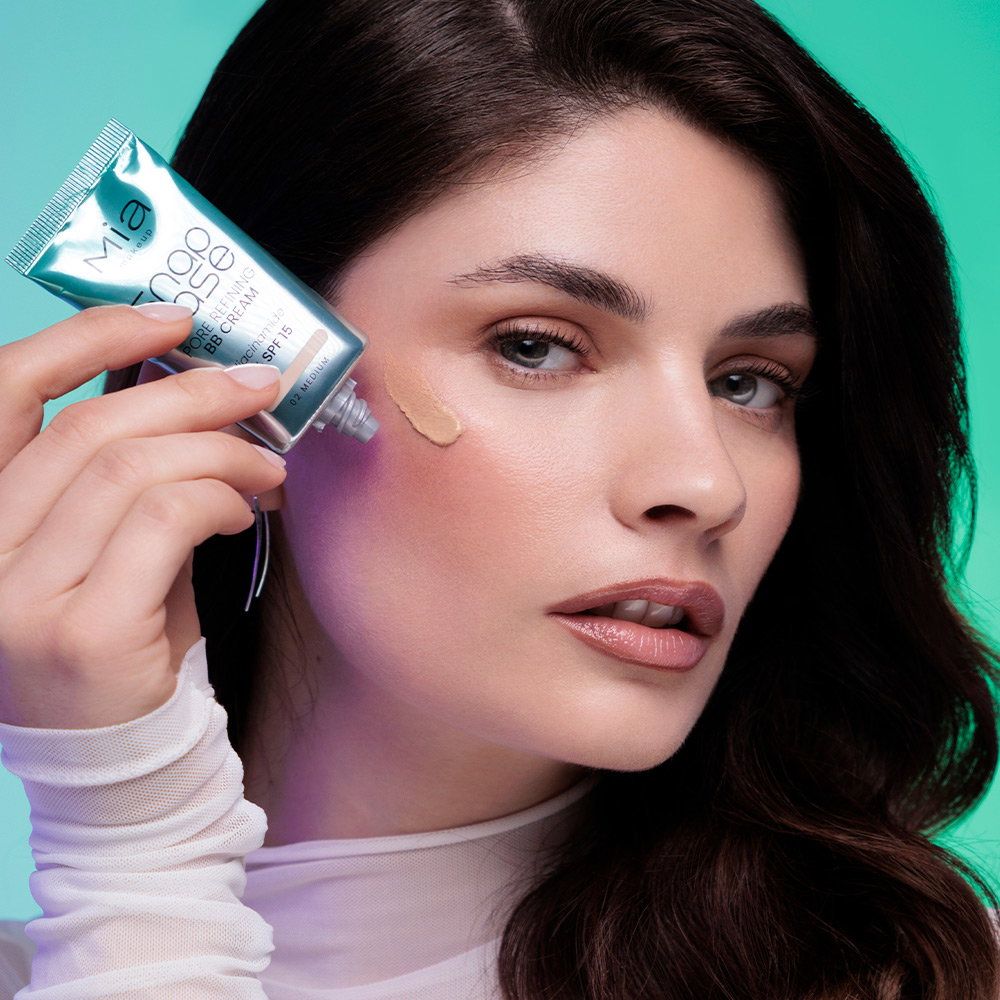 Una donna applica un fondotinta liquido con SPF 15 sulla guancia.