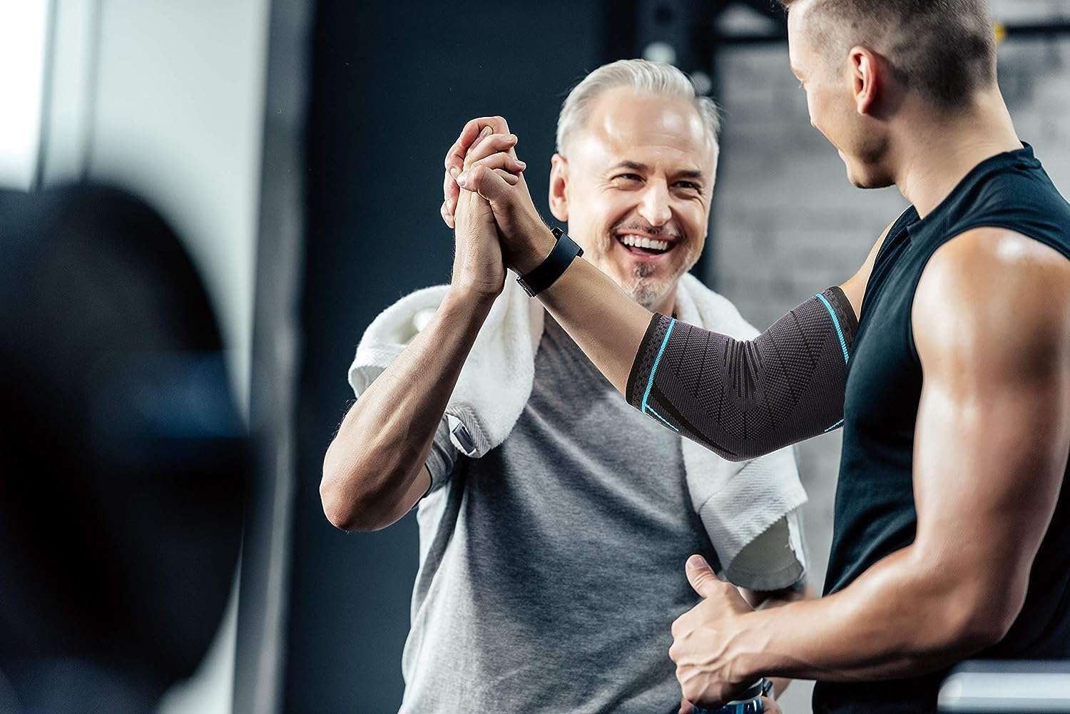 Due uomini in palestra. Uno indossa un tutore per il gomito.