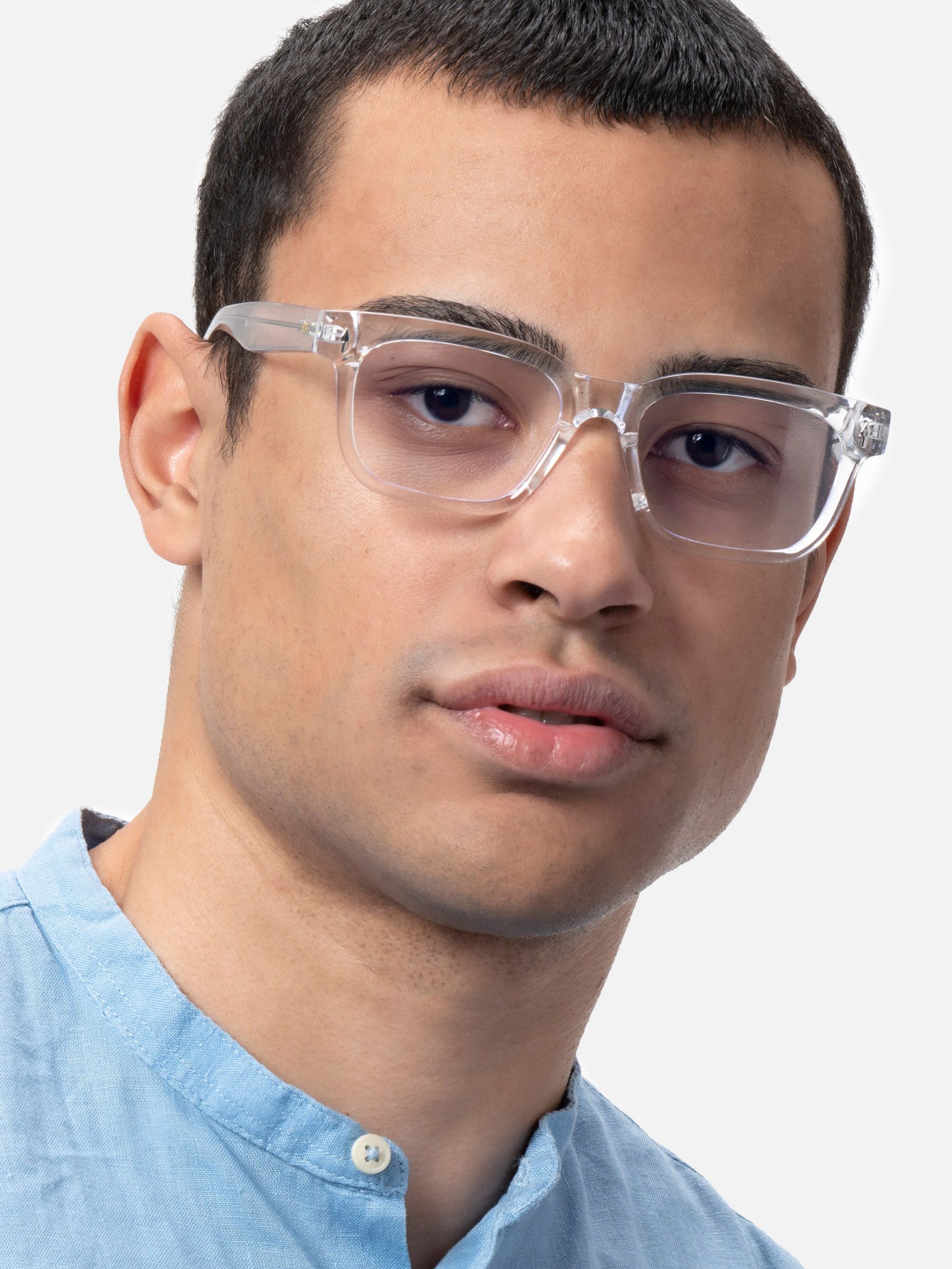 Uomo con occhiali trasparenti con lenti quadrate. Colletto camicia azzurra. Occhiali con logo XFT.