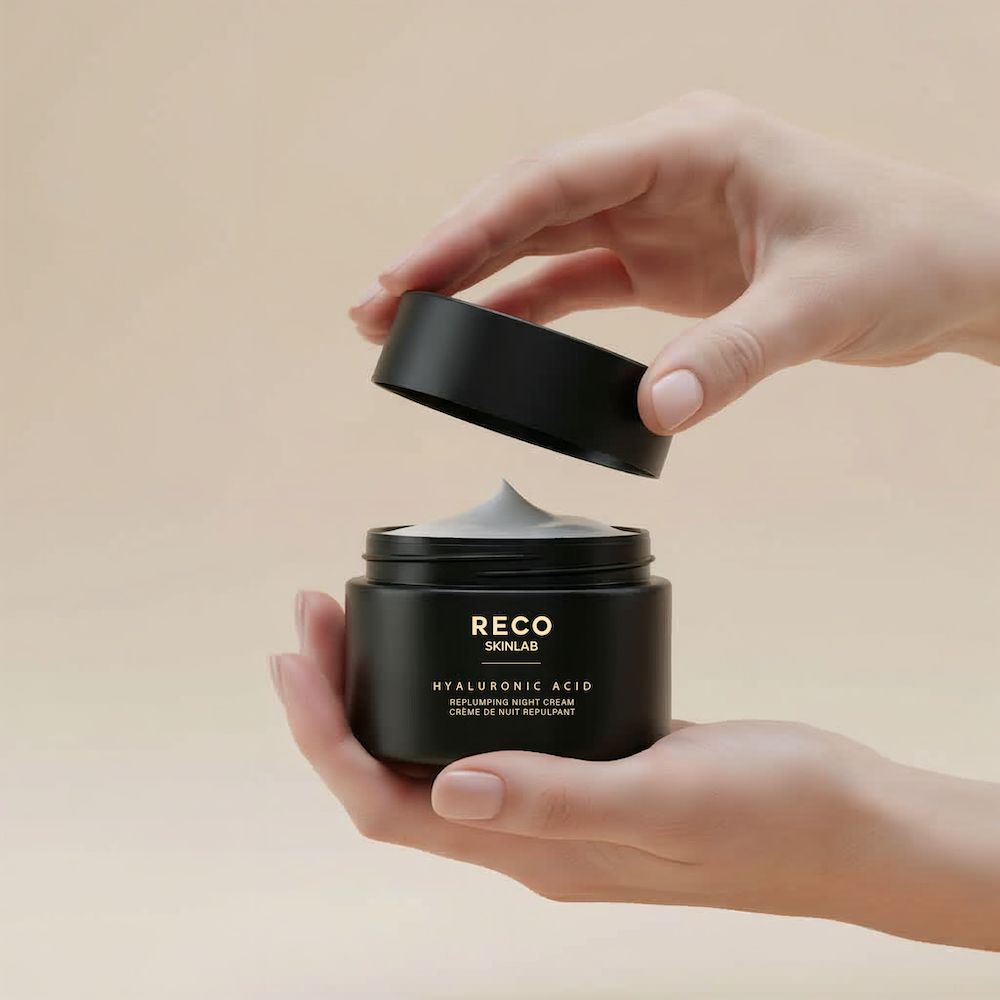 Barattolo nero con coperchio, aperto. Scritta RECO SKINLAB, acido ialuronico, crema notte. Mani che tengono il barattolo e il coperchio.
