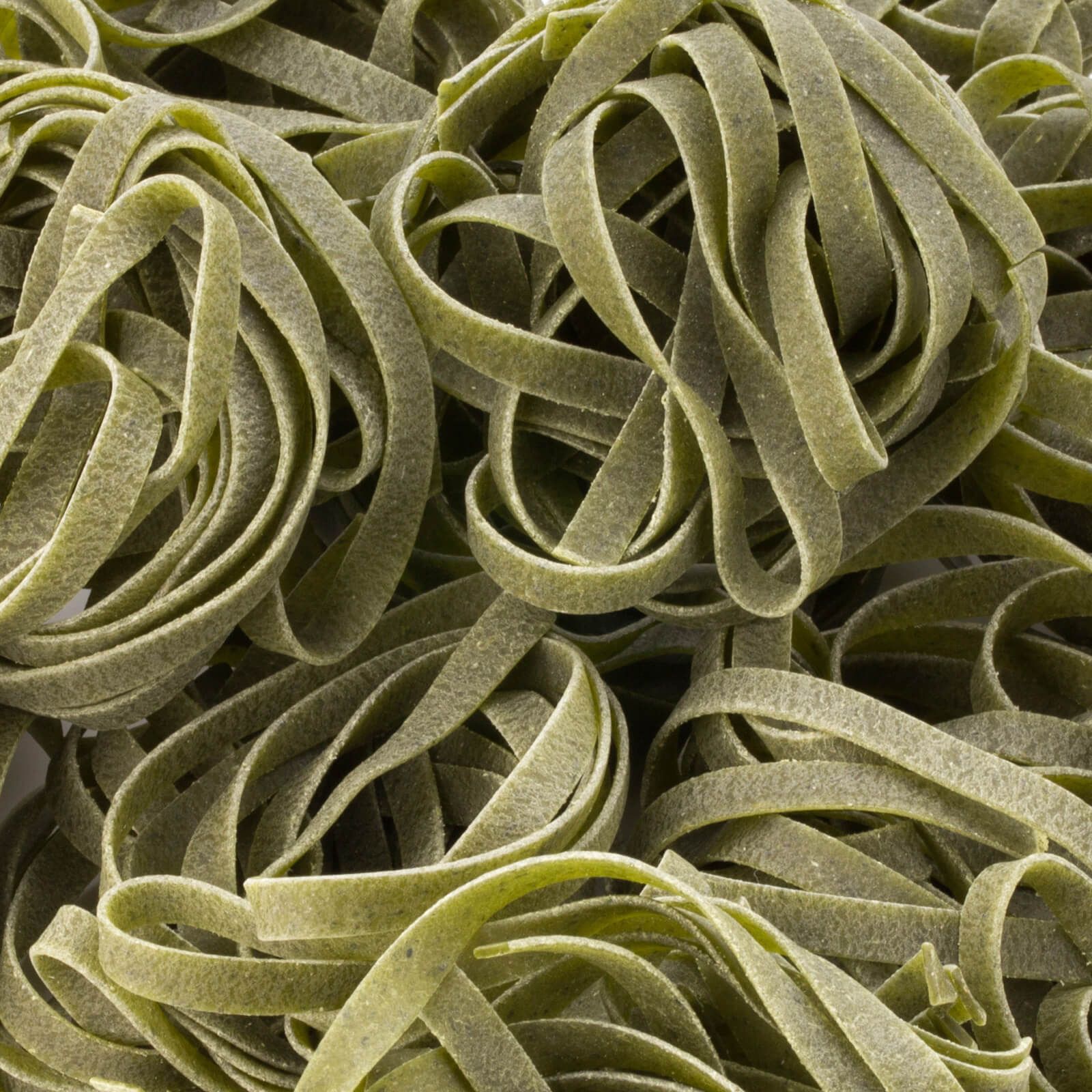 Primo piano di tagliatelle verdi. La pasta è intrecciata.