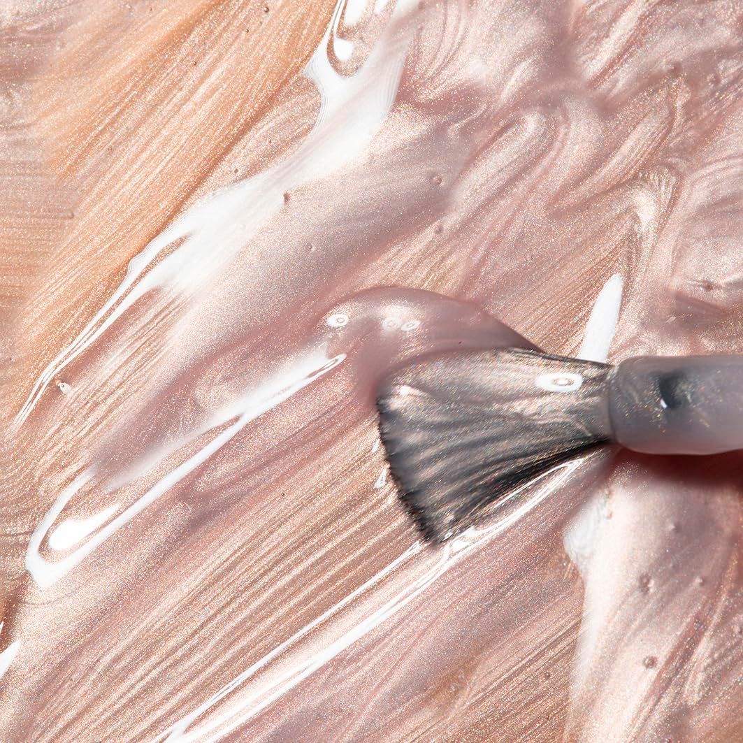 Pennello che traccia una linea di smalto. Smalto beige. Pennello con manico grigio.