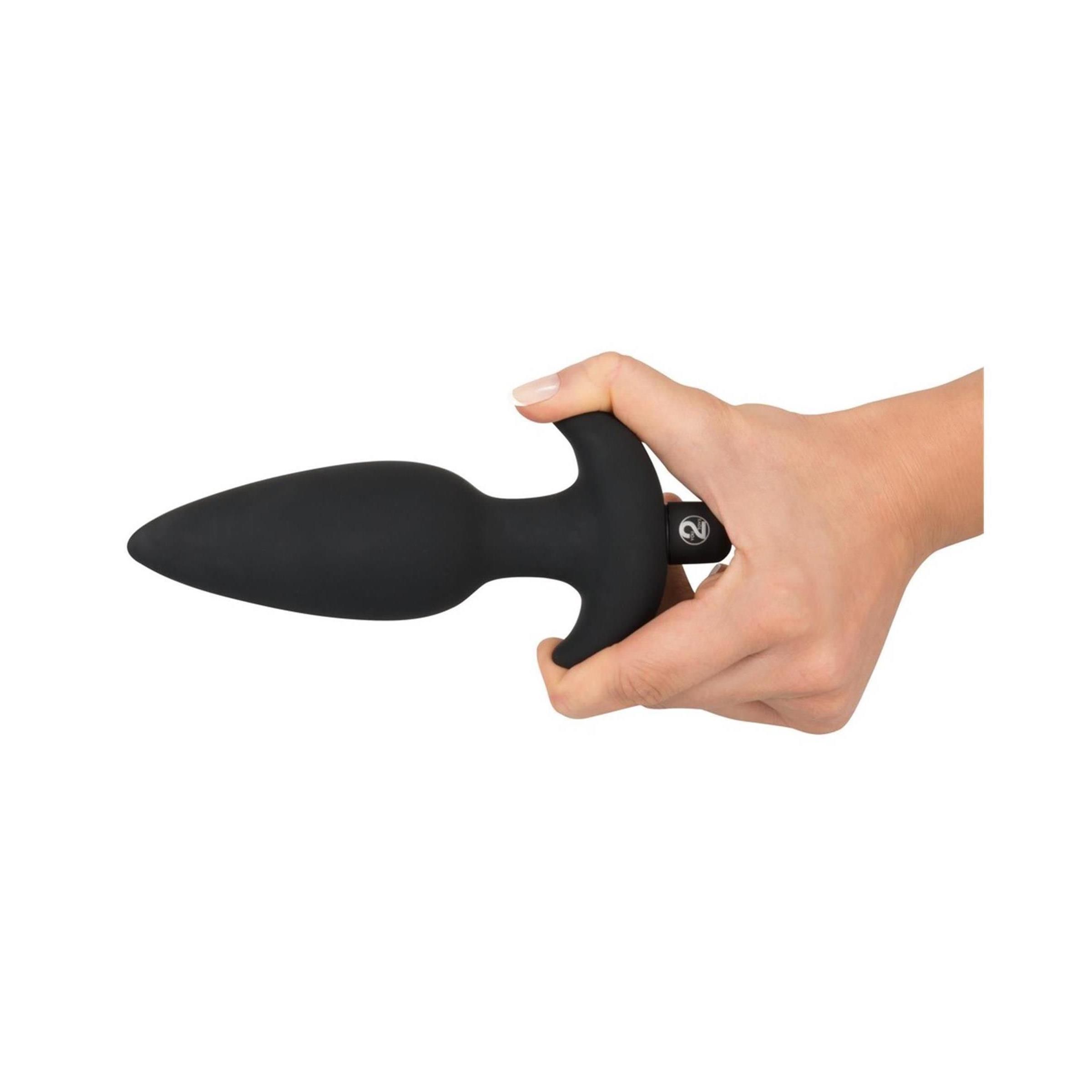 Mano che tiene un plug anale nero. Il plug ha una forma conica, un'impugnatura a T e una base.