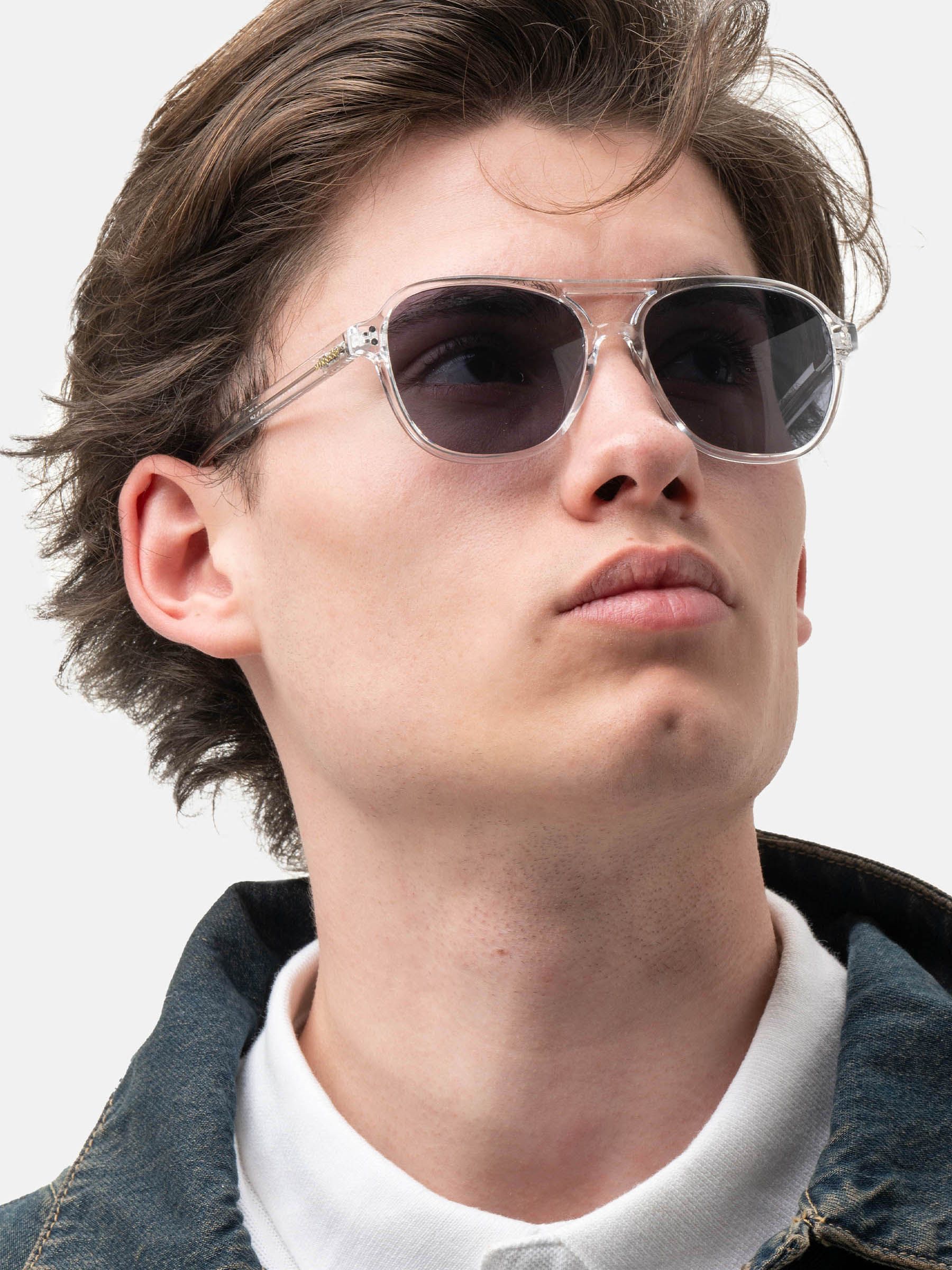Uomo con occhiali da sole Smooder con montatura trasparente e lenti scure. Logo Smooder visibile.