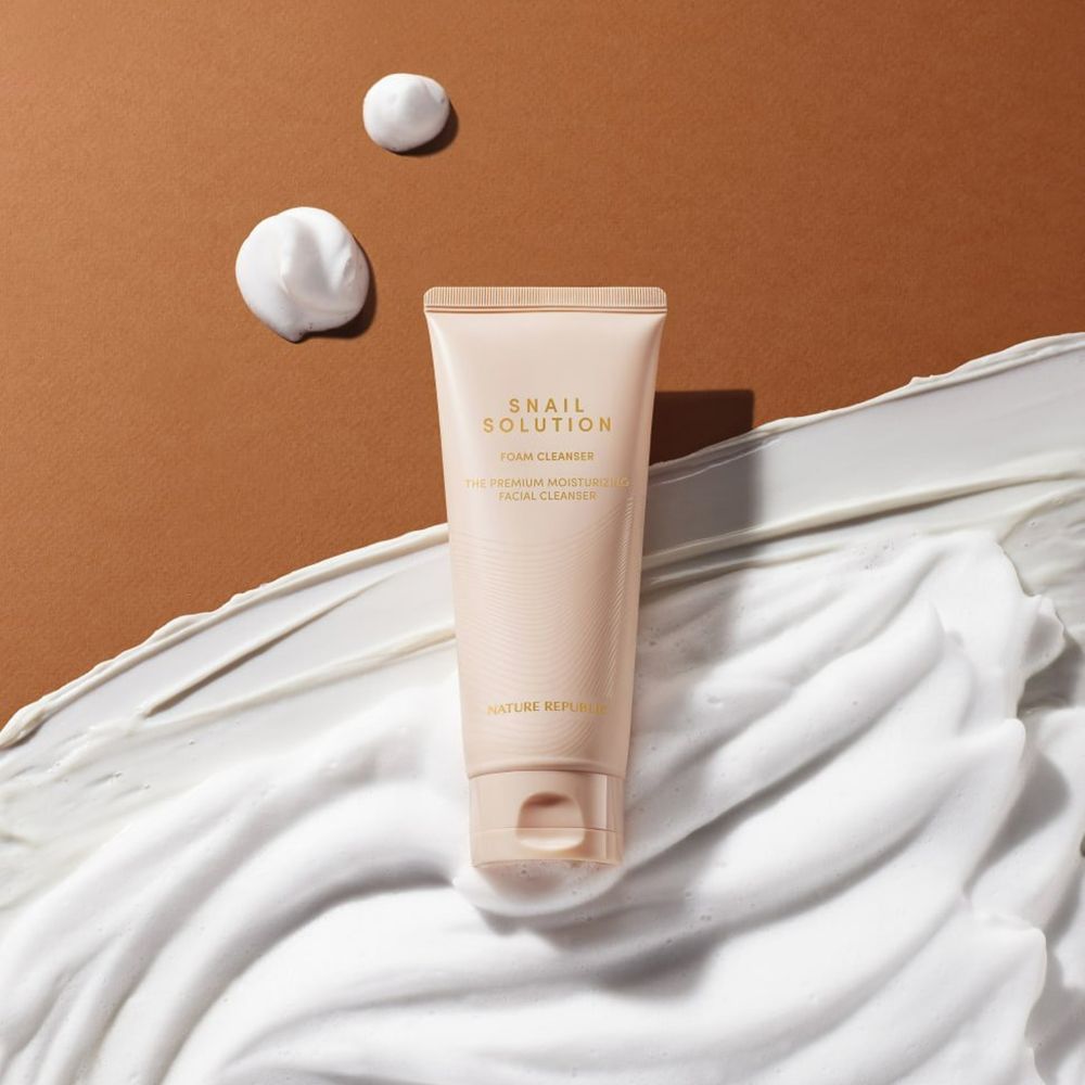 Tubo beige con testo e schiuma. Macchie di schiuma su sfondo marrone.