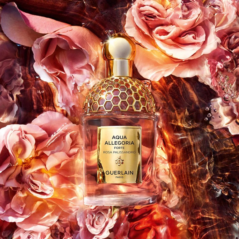Flacone di profumo in acqua con rose. Tappo dorato e motivo a nido d'ape. Etichetta: Aqua Allegoria Forte Rosa Palissandro, Guerlain.