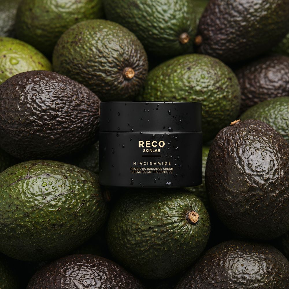 Vaso nero con testo su avocado. Testo: RECO SKINLAB, Niacinamide, Probiotic Radiance Cream, Crème éclat probiotique.