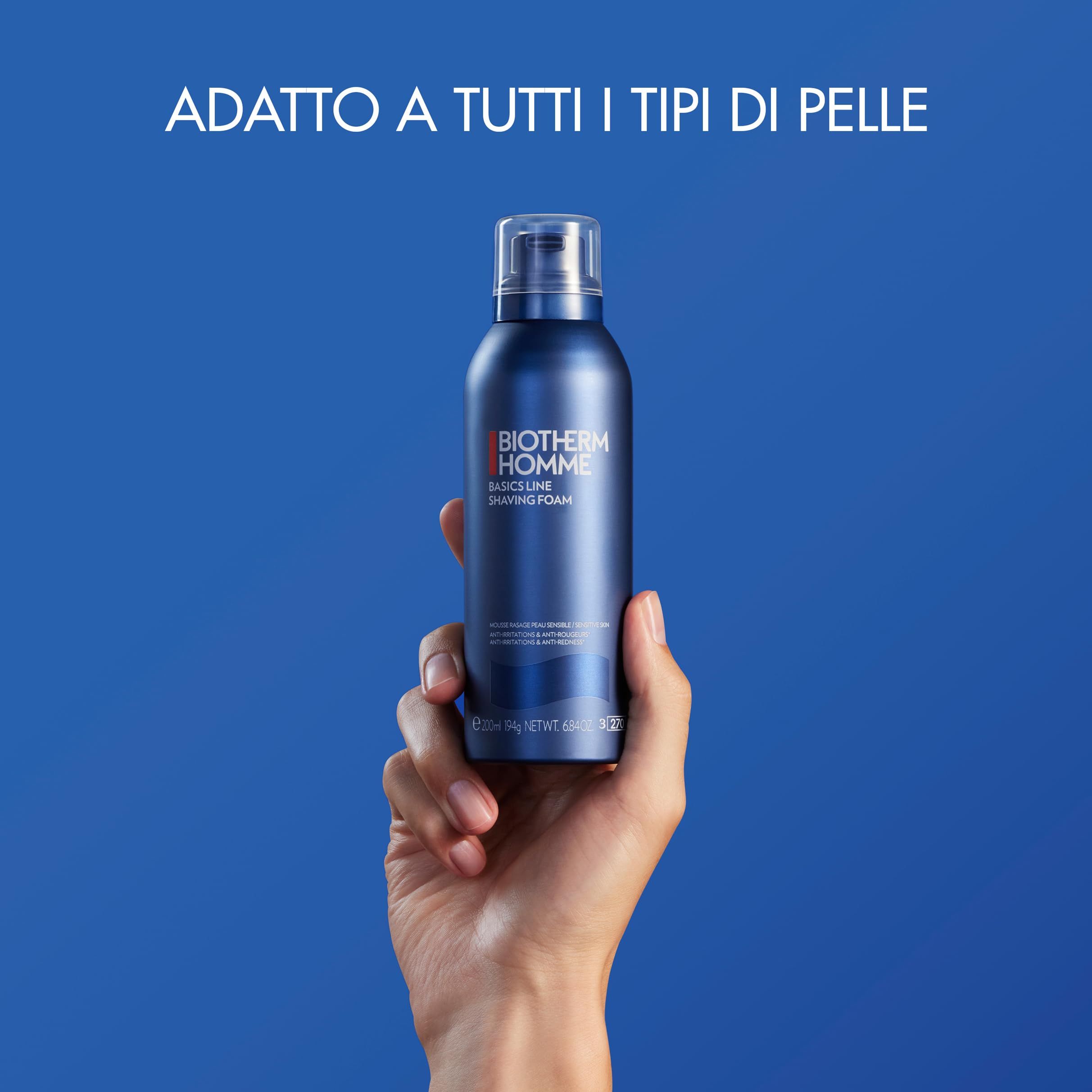 Flacone blu-argento tenuto in mano. Scritta: BIOTHERM HOMME, Basics Line, Shaving Foam. Sfondo blu.