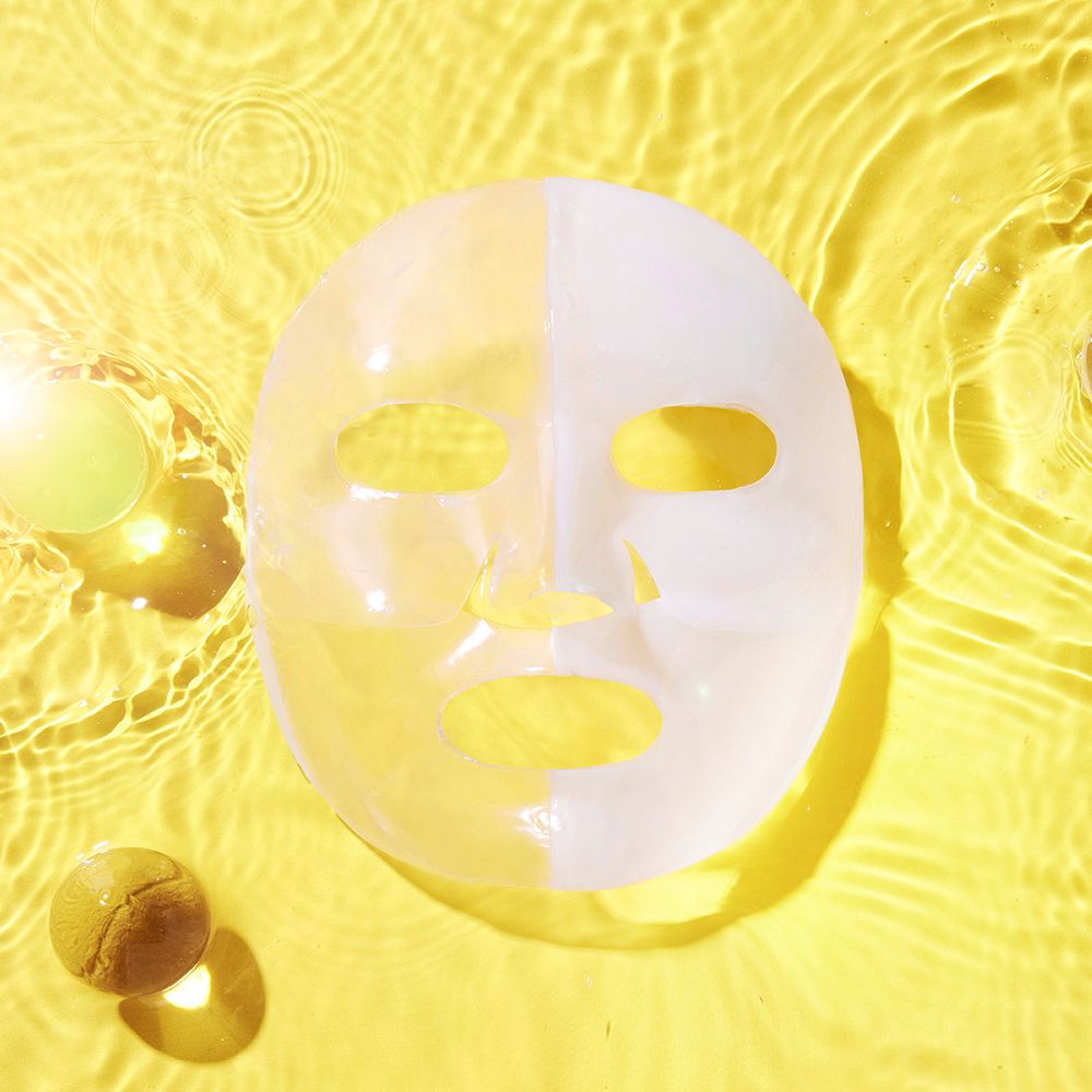 Maschera idrogel Advanced Snail Mucin Glass Glow su sfondo giallo con effetto acqua.