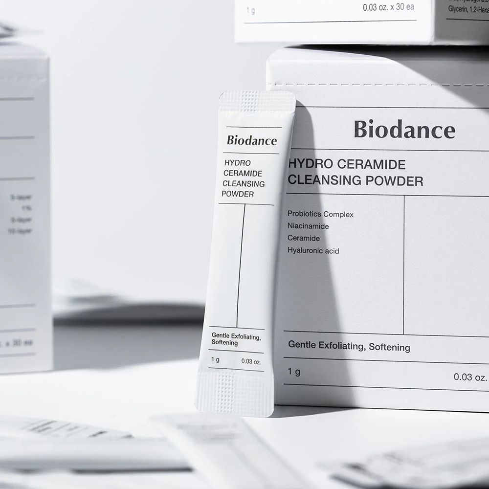 Bustina singola di BIODANCE Hydro Ceramide Cleansing Powder. Scritta: Hydro Ceramide Cleansing Powder. Diverse confezioni sullo sfondo.