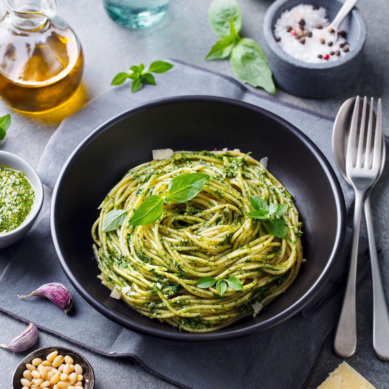 Piatto nero di spaghetti al pesto, basilico, pinoli e parmigiano.