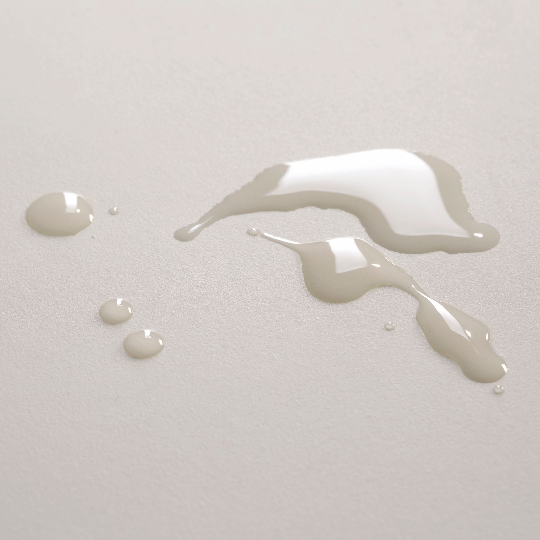 Gocce di olio trasparente su una superficie chiara.