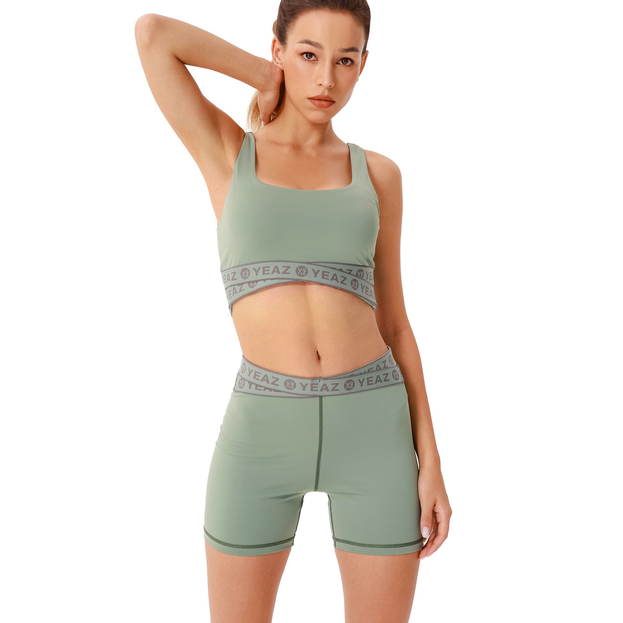 Reggiseno sportivo verde e pantaloncini con logo del marchio grigio in vita.