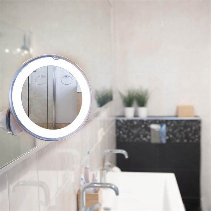 Specchio cosmetico rotondo con illuminazione a LED e ventosa, fissato a uno specchio del bagno.