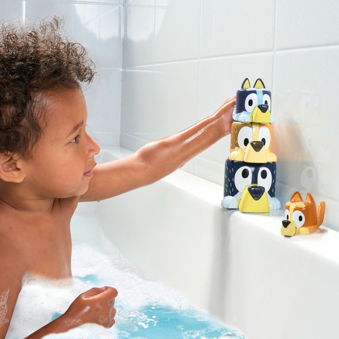 Bambino in vasca da bagno che gioca con giocattoli impilabili a forma di cane. TOMY Bluey.
