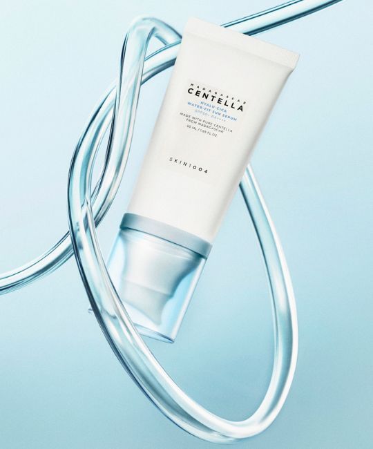 Tubo bianco Madagaskar Centella Hyalu-Cica Water-Fit Sun Serum, circondato da flussi d'acqua.