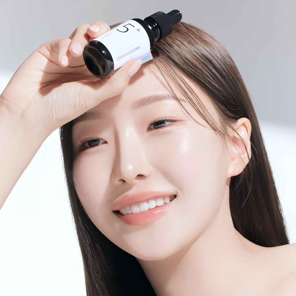 Donna che tiene in mano un flacone nero con pipetta. Etichetta con testo: Vitamin Concentrated Serum, Glutathione. Scritta: 5+.