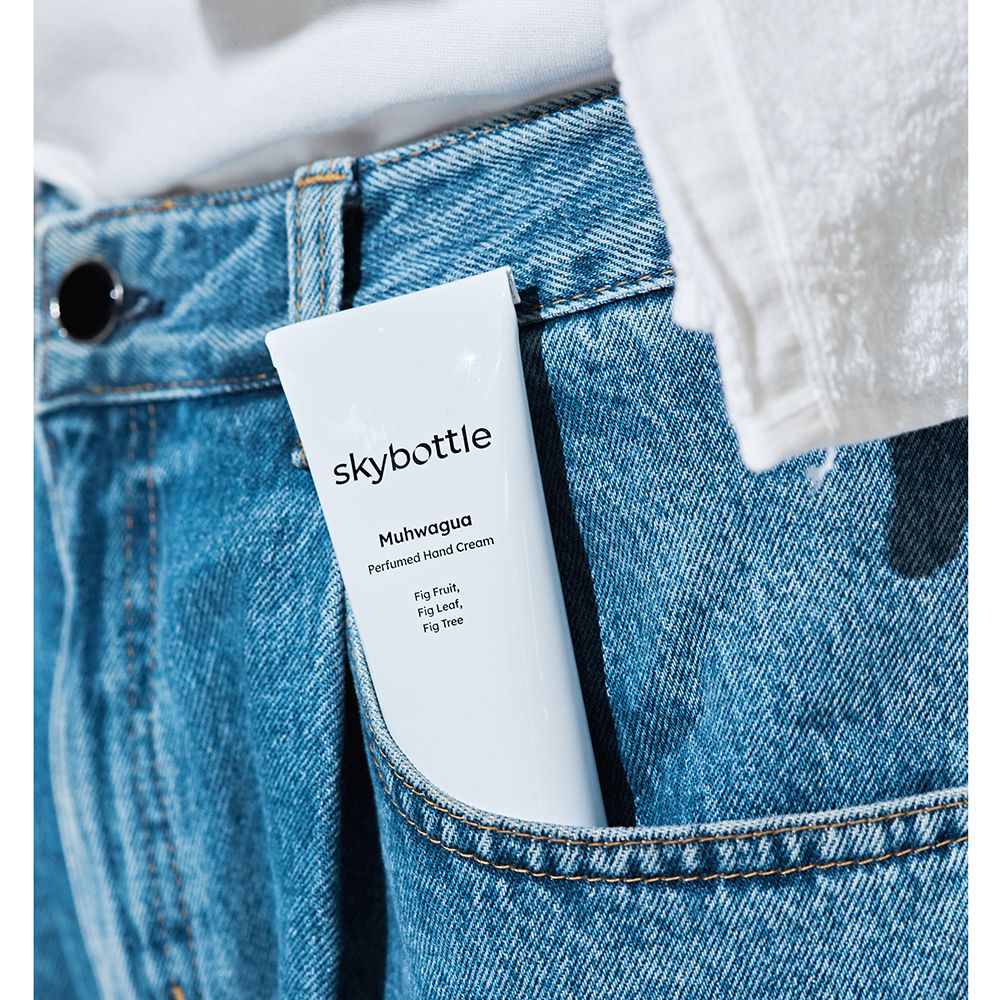 Tubo di crema mani bianco in tasca di jeans. Scritta: skybottle, Muhwagua, Crema mani profumata.