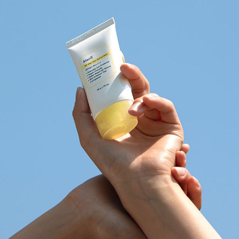 Mani che tengono un tubo bianco con tappo giallo. Scritta: klairs, All-day Airy Sunscreen, SPF50+ PA++++, 50 g.