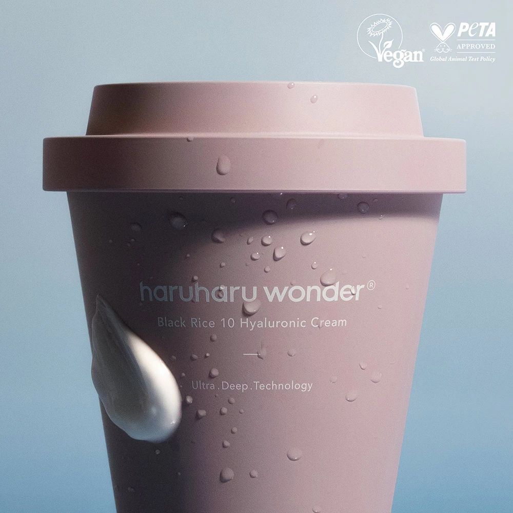 Contenitore di crema rosa con coperchio, gocce d'acqua. Sigilli Vegan e PETA. Testo: haruharu wonder, Black Rice 10 Hyaluronic Cream.