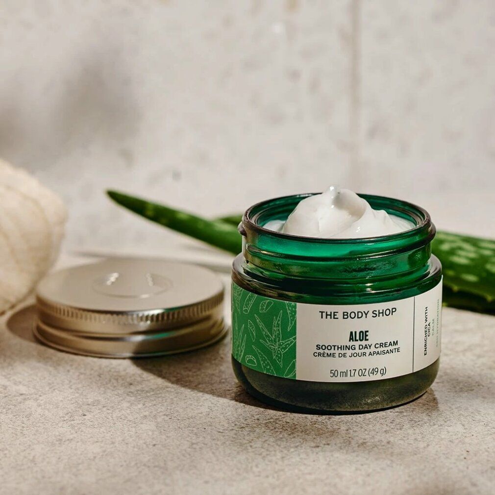 Vasetto verde aperto con crema, accanto coperchio e foglia di aloe vera. Scritta: Aloe Soothing Day Cream.