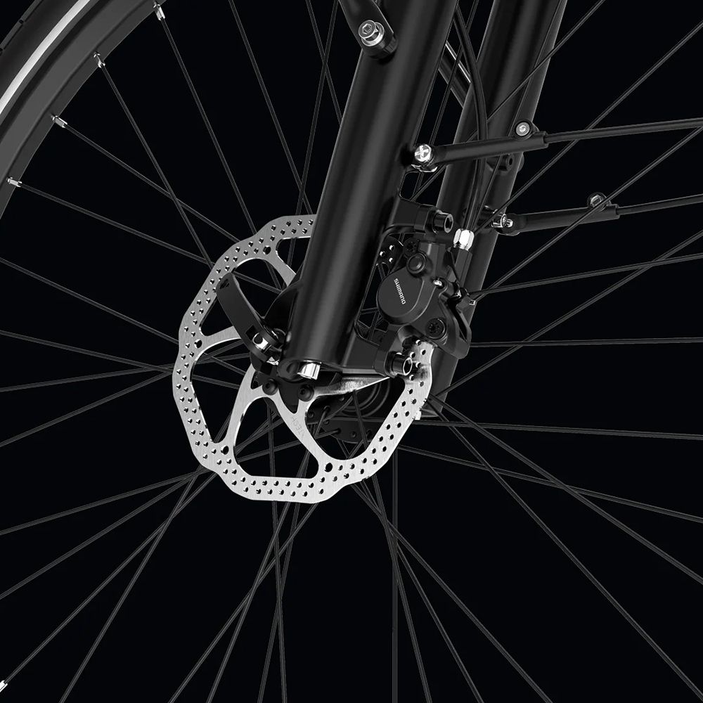 Primo piano del freno anteriore di una e-bike nera. Freno a disco con pinza e raggi.