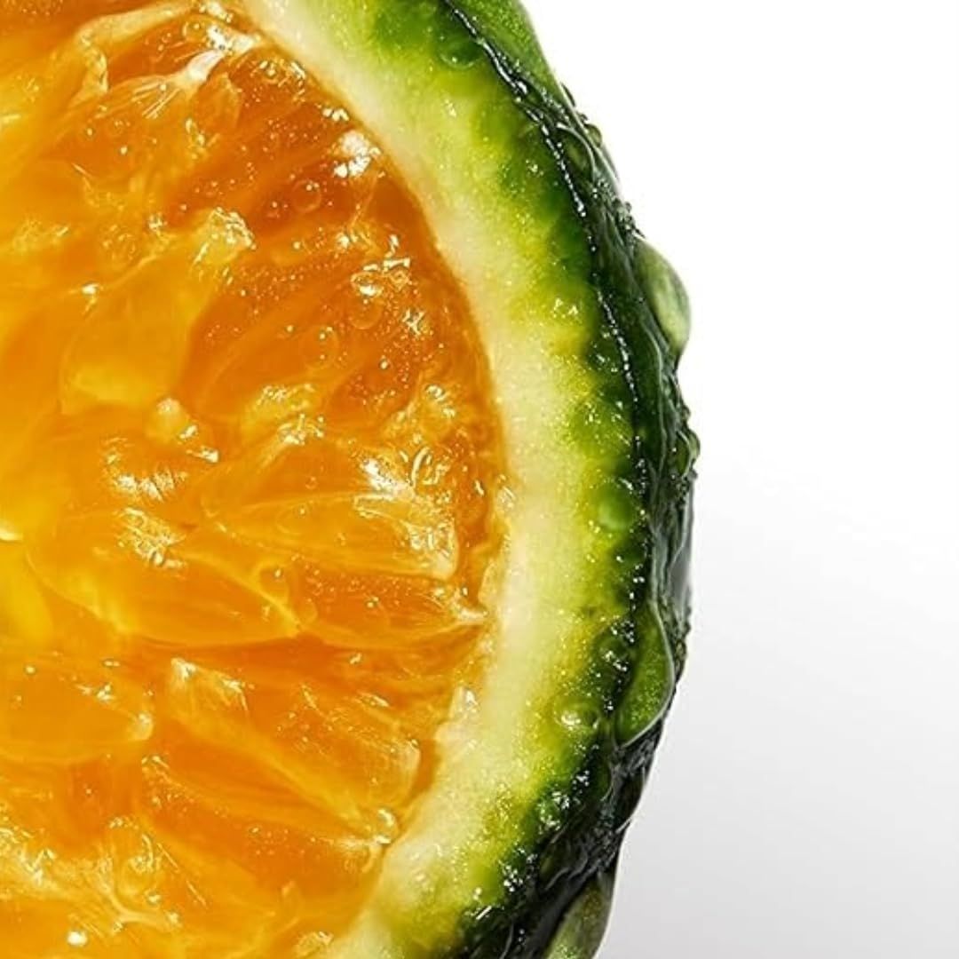 Primo piano di un'arancia tagliata a metà. Polpa, buccia verde con gocce d'acqua.