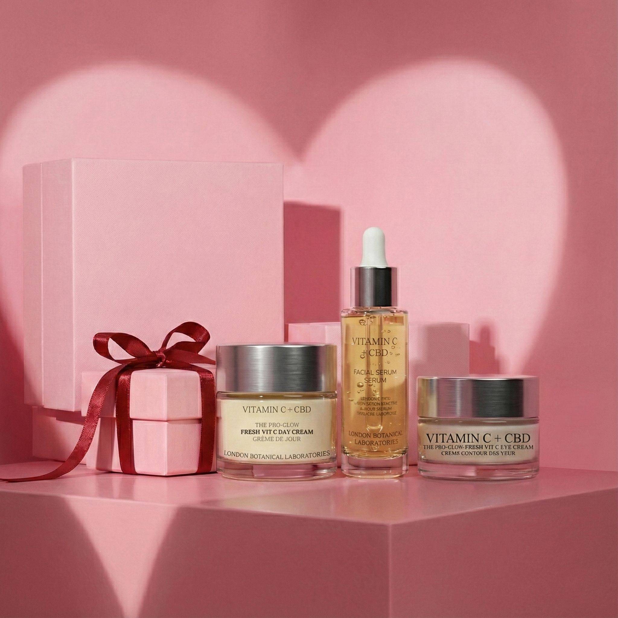 Prodotti cosmetici su piedistallo rosa. Crema giorno, crema occhi e siero. Confezione regalo con fiocco. Sfondo: forma di cuore.