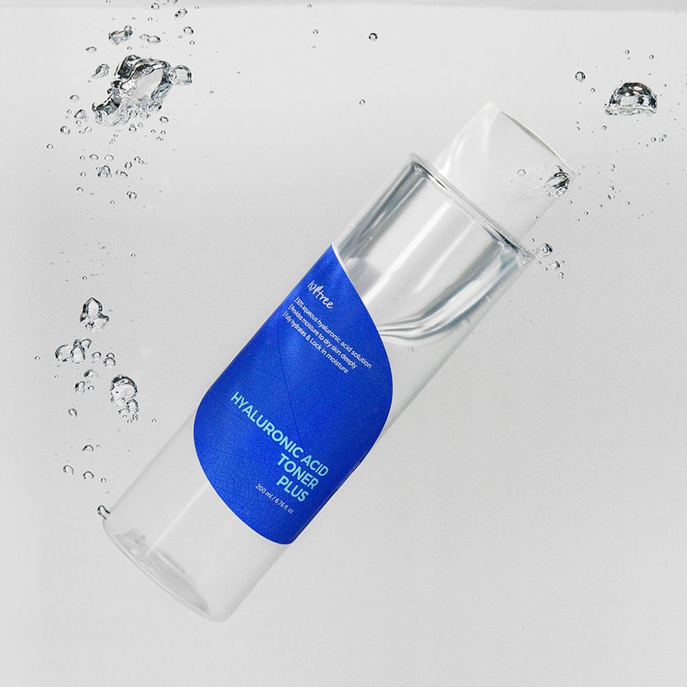 Flacone trasparente con etichetta blu in acqua. Scritta: Hyaluronic Acid Toner Plus. Bolle.