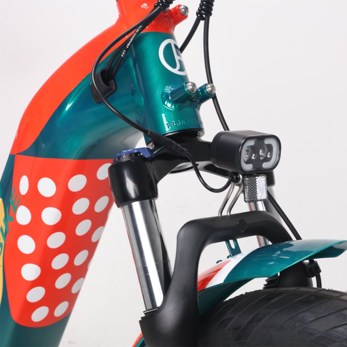 Forcella anteriore e faro di una e-bike. Faro nero, forcella verde. Design verde-rosso. Cavi e dettagli.