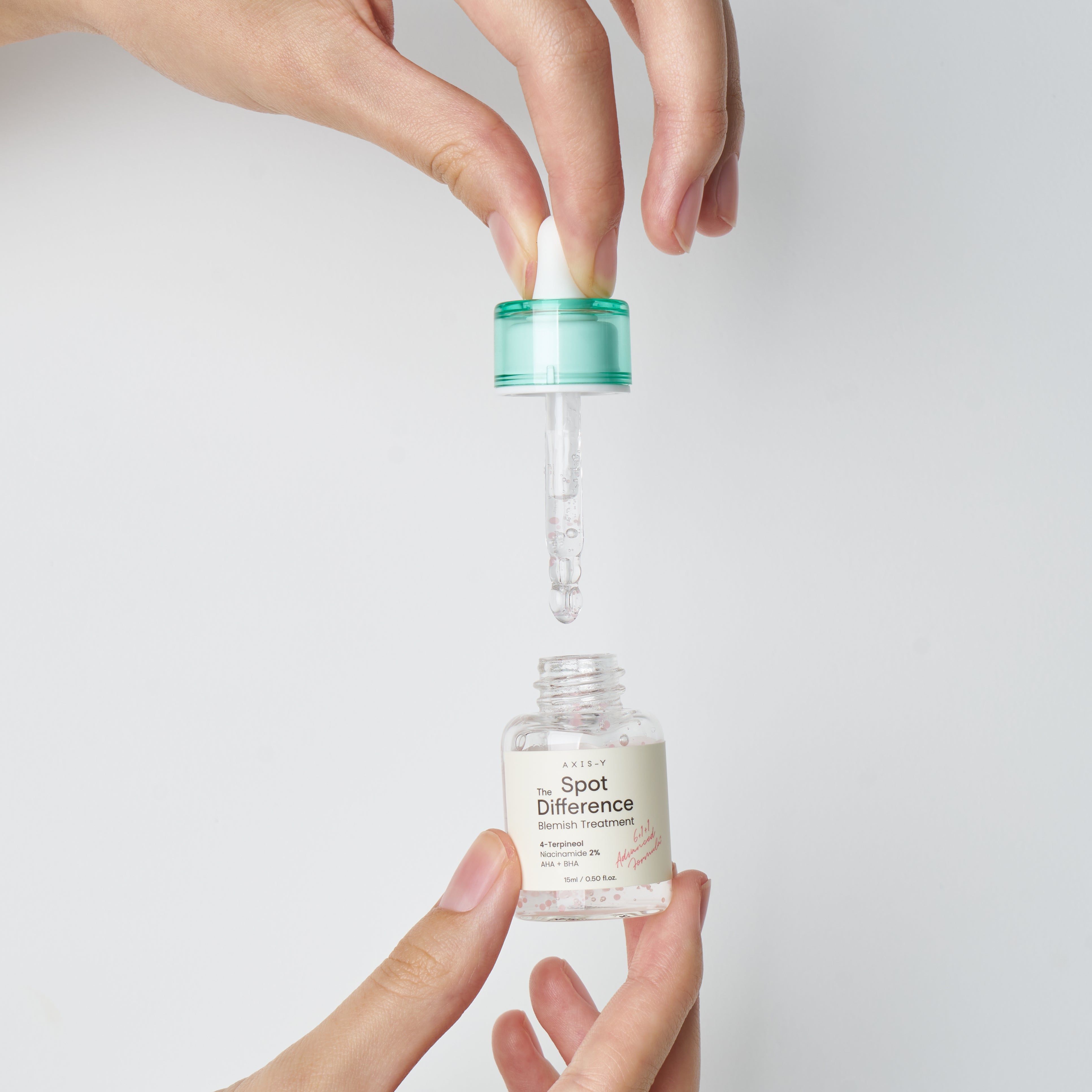 Mani che tengono flacone e pipetta. La pipetta viene inserita nel flacone. Sfondo bianco.