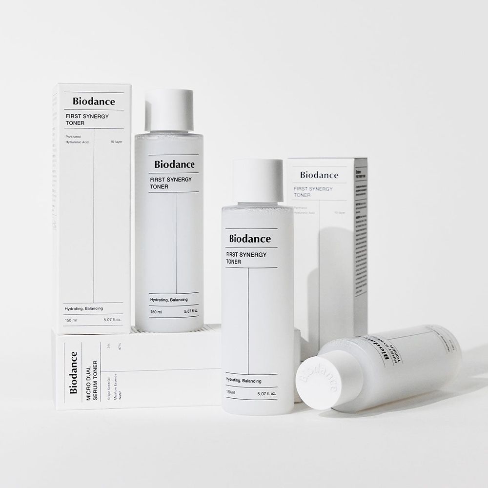 Diversi flaconi e confezioni. Scritta: Biodance First Synergy Toner. 150 ml, Idratante, Riequilibrante.