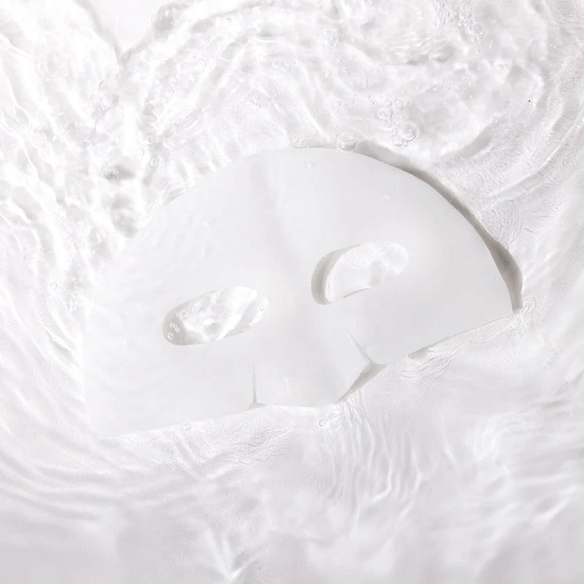 Una maschera facciale bianca galleggia nell'acqua. La maschera ha aperture per occhi e bocca. L'acqua crea onde.