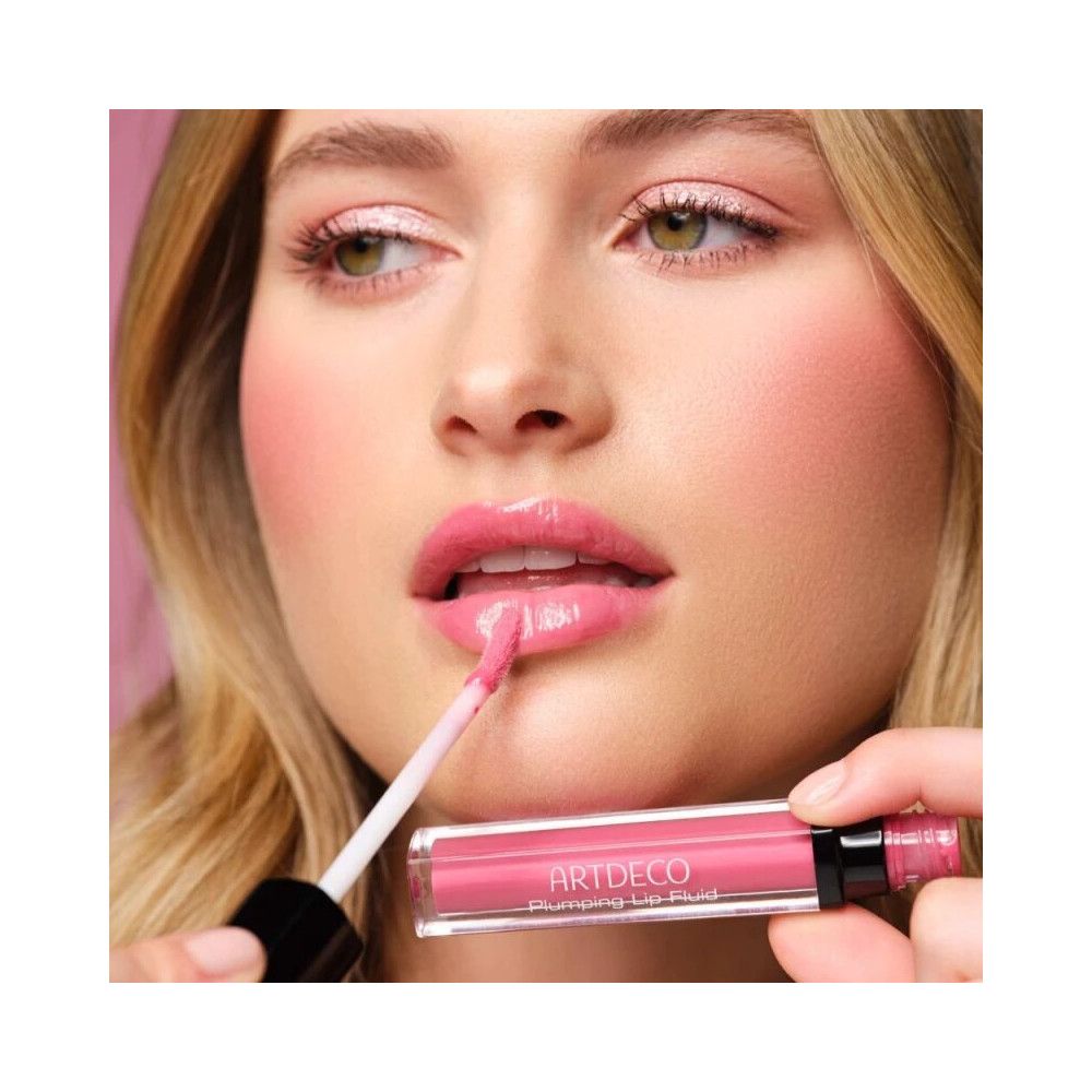 Donna applica Artdeco Lipgloss Plumping Fluid 35 Juicy Berry. Labbra rosa, applicatore.