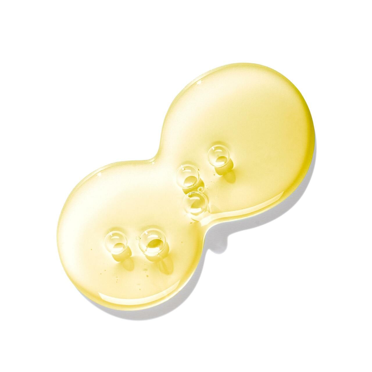 Liquido giallo a forma di goccia con bolle su sfondo bianco.