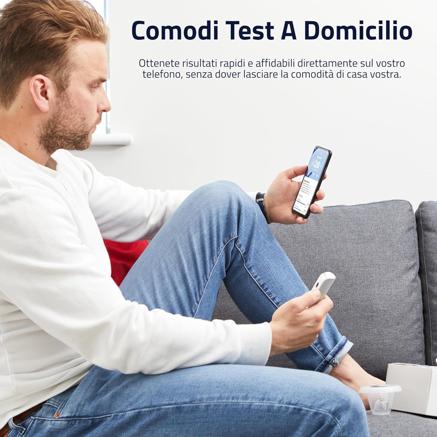 Uomo seduto sul divano, tiene in mano smartphone e dispositivo di test. Risultati del test sullo schermo. Marchio sul dispositivo.
