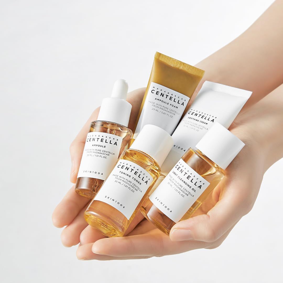 Mani che tengono cinque piccole bottiglie e tubetti cosmetici con estratti di Centella.
