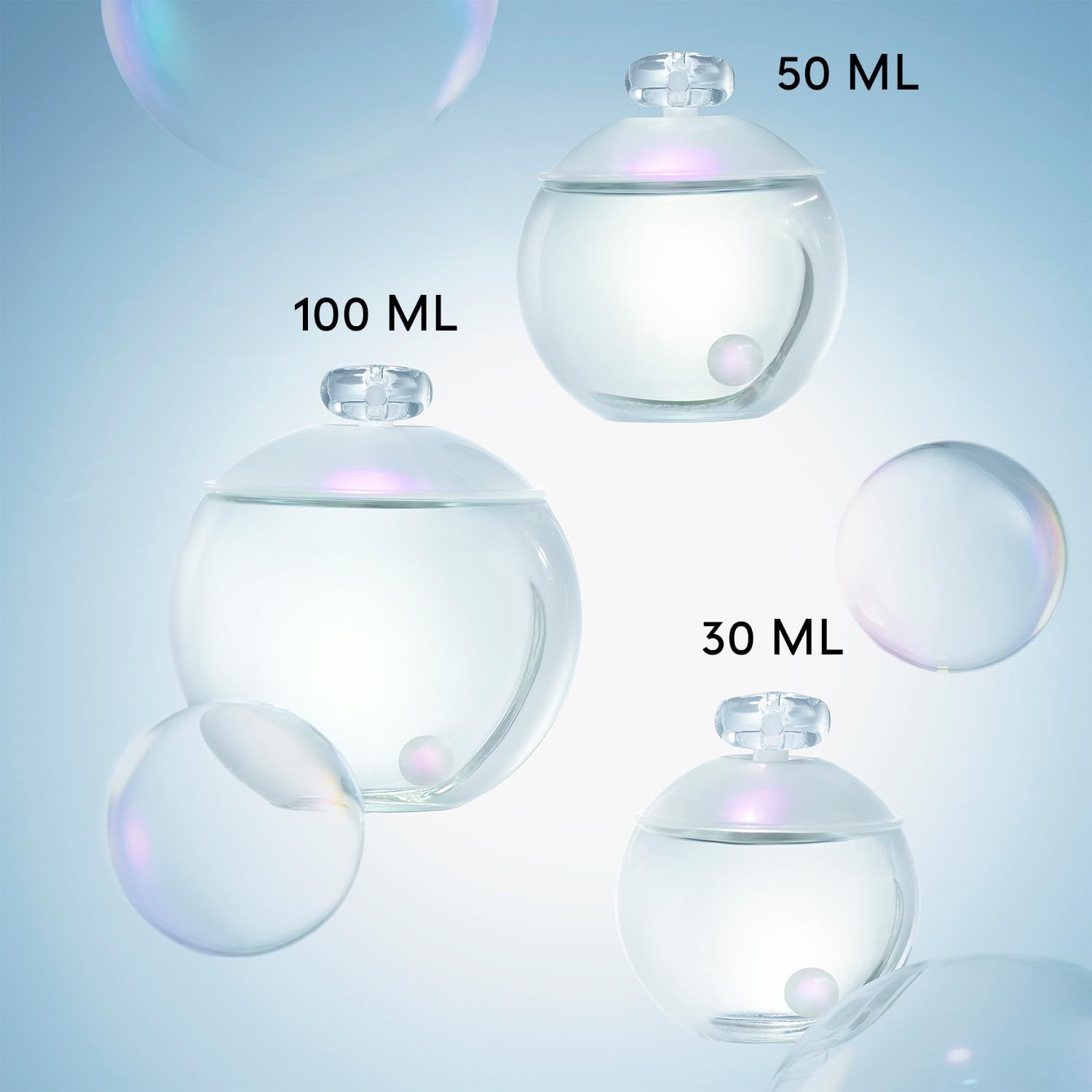 Tre flaconi di profumo di diverse dimensioni. Flaconi rotondi e trasparenti con tappo. Etichette delle dimensioni.