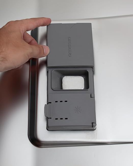 Mano apre vano detersivo grigio. Un tab all'interno.