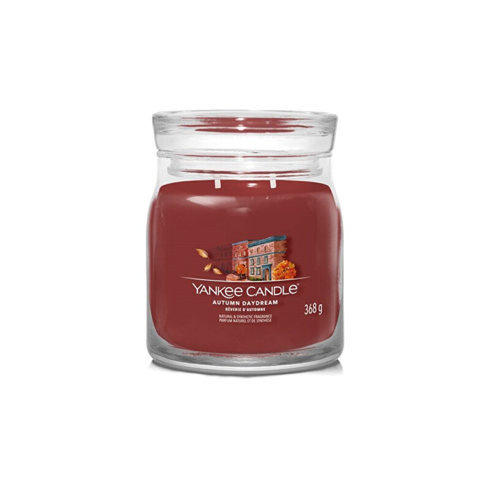 Candela profumata in vaso. Cera rossa, contenitore in vetro trasparente con coperchio. Scritta: Yankee Candle, Autumn Daydream, 368 g.